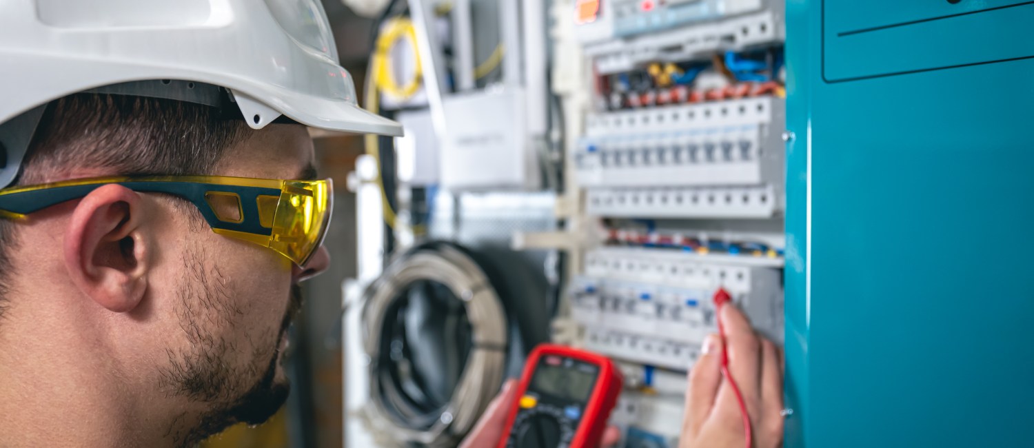 Man, an electrical technician working in a switchboard with fuses.