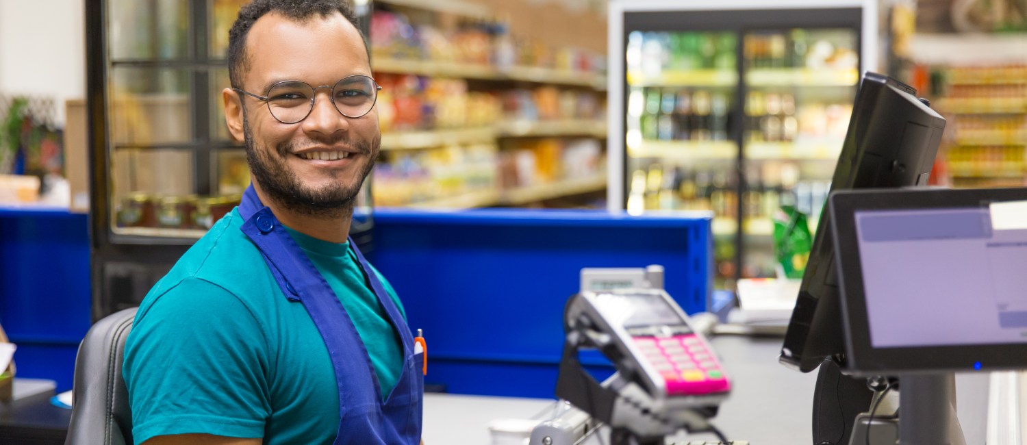 Smiling African American cashier sitting at checkout